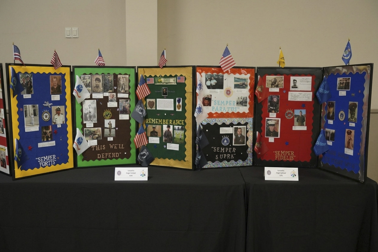 A row of six colorful trifold display boards stands on a black-draped table indoors.